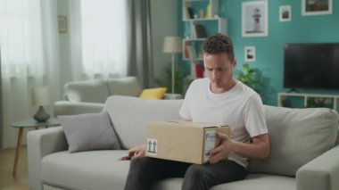 Genç bir adam içinde hiçbir şey olmayan bir karton parsel açar