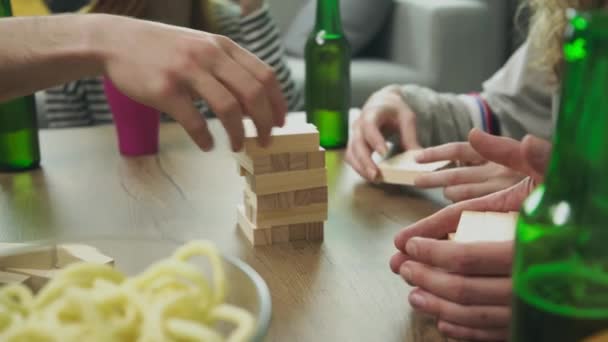 Firma przyjaciół odgrywa drewnianą wieżę w przytulnym salonie — Wideo stockowe