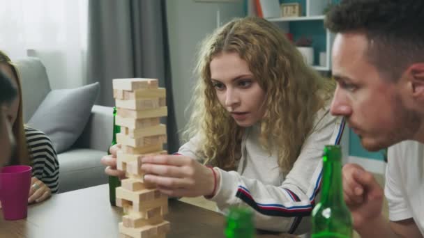 Een gezelschap van vrienden speelt een houten toren in een gezellige woonkamer — Stockvideo