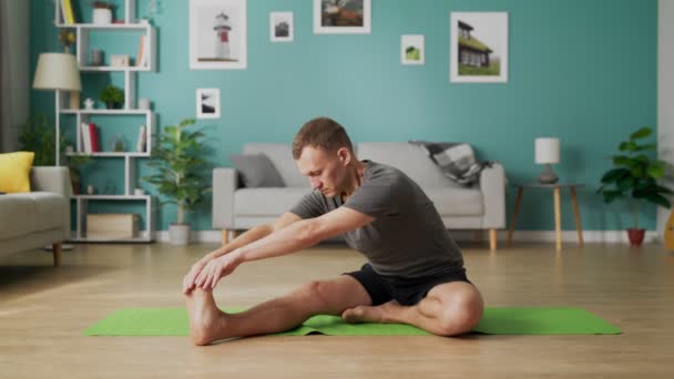 Середній знімок молодого чоловіка робить йогу вранці у своїй вітальні — стокове відео
