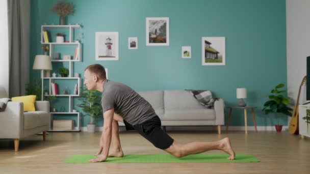 Joven haciendo yoga por la mañana en su sala de estar — Vídeo de stock