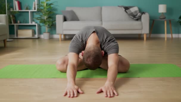 Jongeman die 's morgens yoga doet in zijn woonkamer — Stockvideo