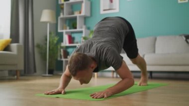 Genç adam sabah yoga yapıyor. Oturma odasında.