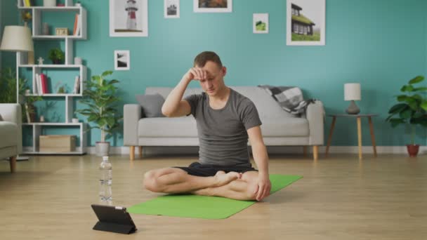 Man dricksvatten från en flaska under yogalektioner online — Stockvideo