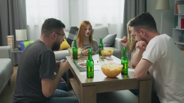 Друзья играют в стратегическую настольную игру с картами и костями в уютной гостиной — стоковое видео