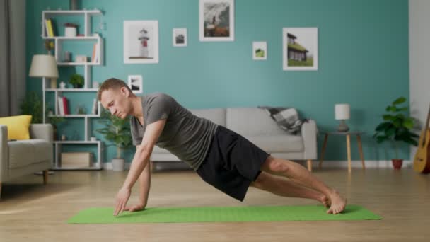 El hombre está haciendo yoga en casa por la mañana en su sala de estar — Vídeos de Stock