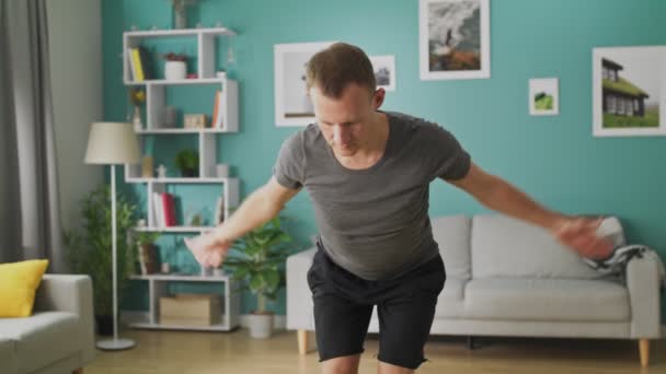 El joven está haciendo yoga en la sala de estar por la mañana. — Vídeos de Stock