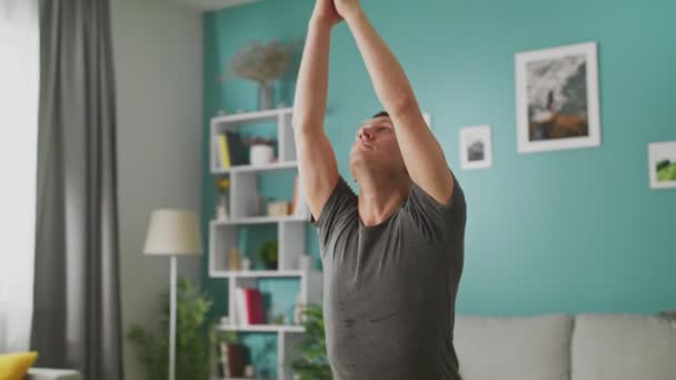 El hombre está haciendo yoga en casa por la mañana en su sala de estar — Vídeo de stock