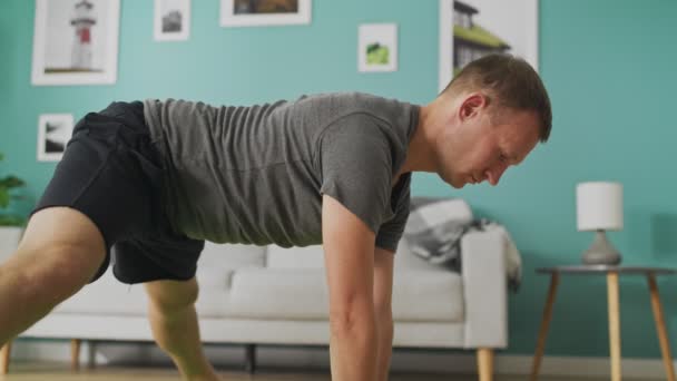Ung man gör yoga i vardagsrummet på morgonen — Stockvideo