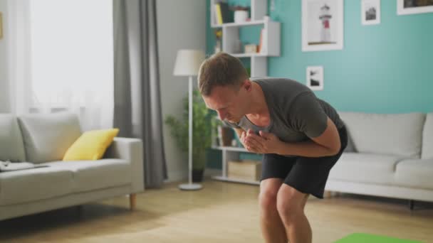 El hombre está haciendo yoga en casa por la mañana en su sala de estar — Vídeo de stock