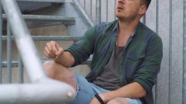 Şehirde merdivenlerde sigara içen adam