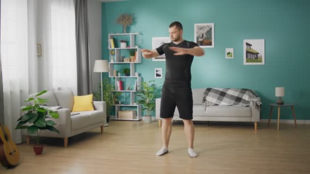 Молодой человек делает упражнения в своей гостиной — стоковое видео