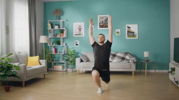 Молодий чоловік робить вправи у своїй вітальні — стокове відео