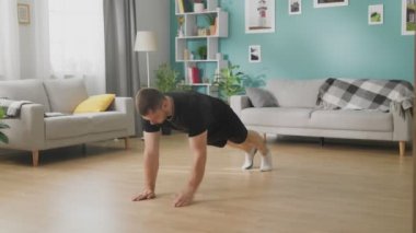 Oturma odasında egzersiz yapan genç adam