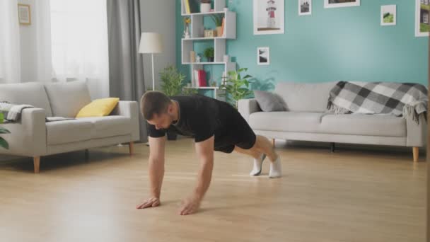 Jonge man doet oefeningen in zijn woonkamer — Stockvideo