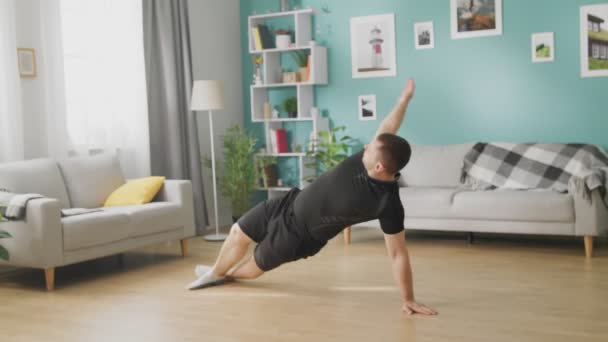 Ung man gör övningar i sitt vardagsrum — Stockvideo