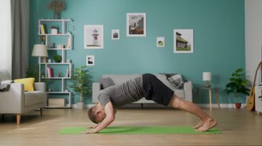 Evde yoga yapan genç adam.