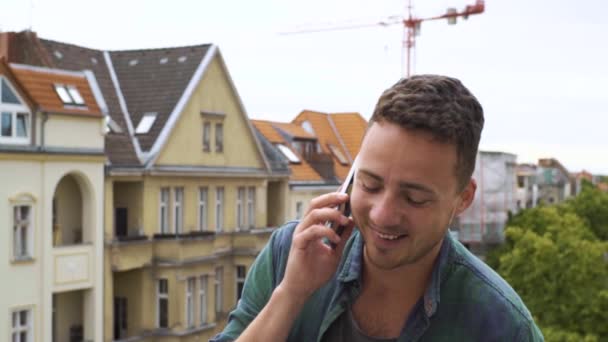El tipo con el teléfono en el balcón de la ciudad — Vídeos de Stock