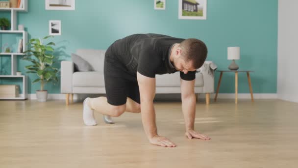 Young man is doing exercises on floor of modern apartment — Stock Video