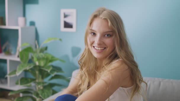 Retrato de jovem senhora feliz olhando para a câmera e sorrindo na acolhedora sala de estar — Vídeo de Stock