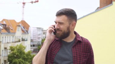 Şehirde balkonda telefon olan adam.