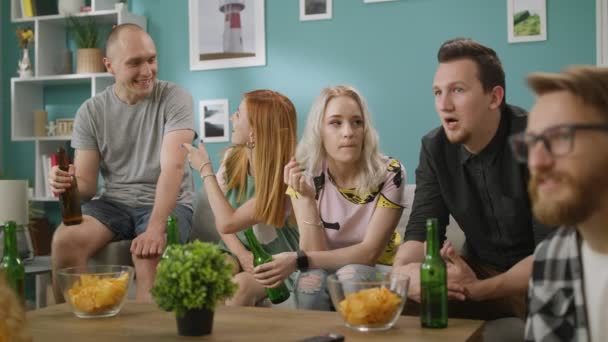 En la sala de estar Grupo de amigos en ver la televisión, y bebe cerveza con bocadillos — Vídeo de stock