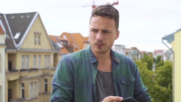 Man het typen van SMS op een balkon in een grote stad — Stockvideo