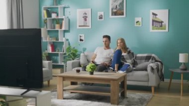 Canı sıkılan genç çift kanepede televizyon izliyor