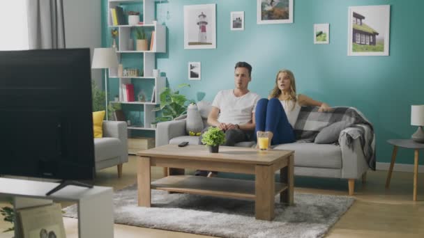 Mladí manželé sledují strašidelný film v televizi na gauči v útulném obývacím pokoji — Stock video