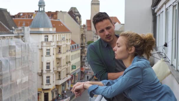 Ζευγάρι στο μπαλκόνι ενός ξενοδοχείου στο κέντρο μιας μεγάλης πόλης σε ένα ταξίδι — Αρχείο Βίντεο