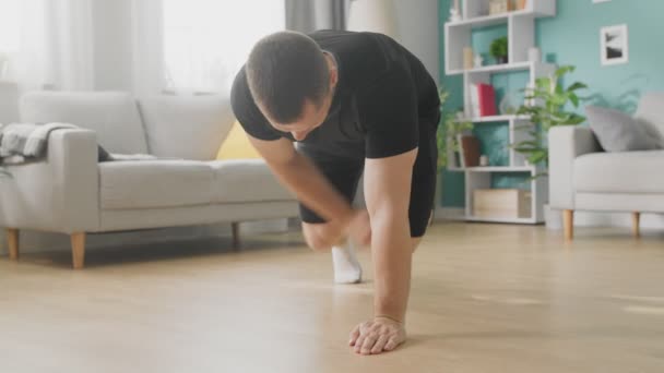En ung man som gör gymnastik på eftermiddagen i sitt vardagsrum — Stockvideo