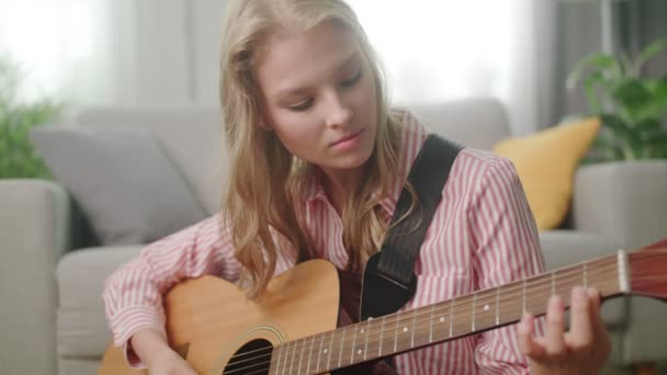 Красивая женщина играет на гитаре в его гостиной — стоковое видео
