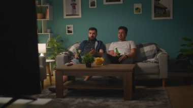 Genç erkekler konuşurken ve TV 'de spor oyunu izlerken üzgün almak