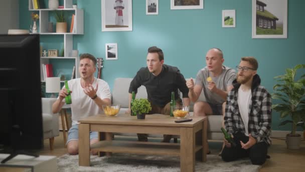 Vier männliche Freunde versammeln sich, um Fußballwettkämpfe im Fernsehen zu sehen, Sofa-Experten — Stockvideo