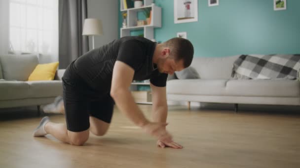 Молодой человек делает упражнения днем в своей гостиной — стоковое видео