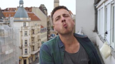 Büyük bir şehirde bir otel balkonunda hamburger yiyen adam