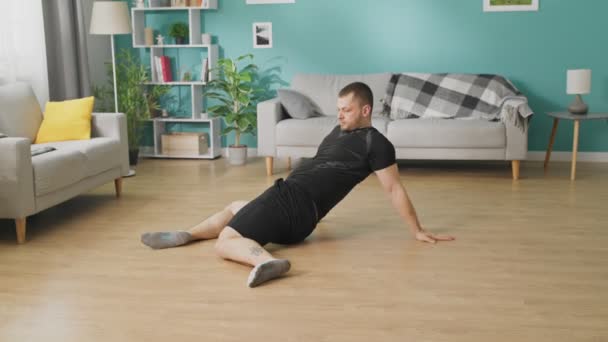 Öğleden sonra oturma odasında jimnastik yapan genç bir adam — Stok video