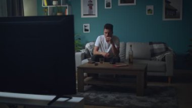 Adam geceleri kanepede evde dinleniyor, Sigara içiyor ve TV izliyor.