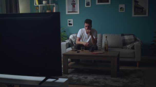 Мужчина отдыхает дома на диване ночью, курит и смотрит телевизор — стоковое видео