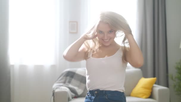 Portrait of happy young lady looking at camera and smiling in cozy living room — Stock Video