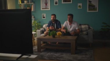 Televizyon önünde iki arkadaş kanepede oturan spor bir oyun saatler