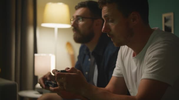 Abends zwei Freunde auf einem Sofa im Wohnzimmer und spielen Videospiele — Stockvideo