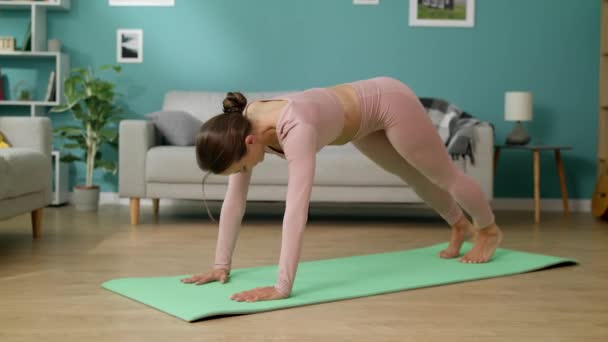 Mujer joven haciendo ejercicio en casa practicando hacia abajo frente a la pose del perro en casa — Vídeos de Stock