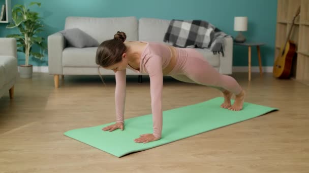 Frau macht Yoga-Übungen im Wohnzimmer, nach unten gerichtete Hundehaltung — Stockvideo