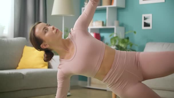 Hermosa mujer está haciendo ejercicios de yoga en casa, tablón de pie en casa en el suelo — Vídeos de Stock
