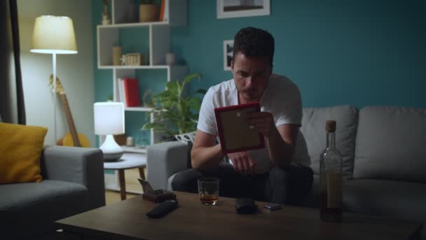 Sad man looking at photo of ex-girlfriend, regretting break-up and drink alcohol — Stock Video