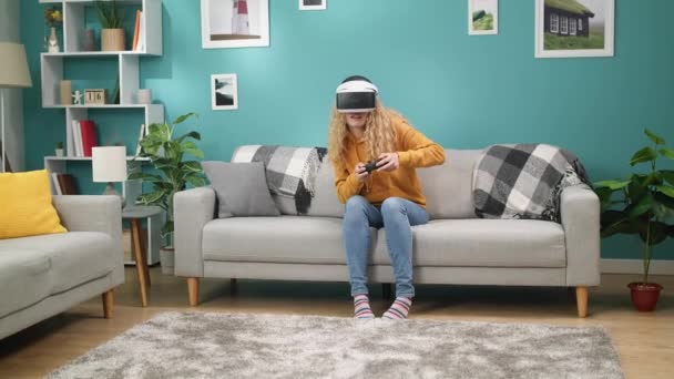 Mujer con capucha amarilla y gafas VR juega juegos de acción en la consola de juegos — Vídeos de Stock