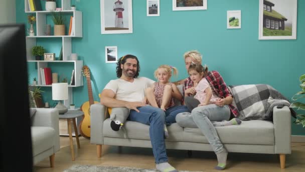 ソファに座って自宅で幸せな家族の時計の映画 — ストック動画