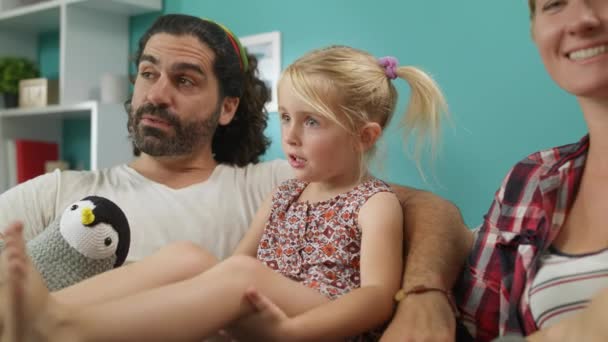 Mutlu aile anne baba ve kızları birlikte kanepede oturup tv programı izlemek — Stok video