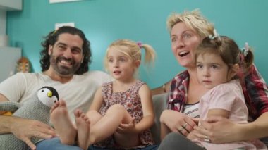 Mutlu aile anne baba ve kızları birlikte kanepeye oturup komik tv programı izlemek